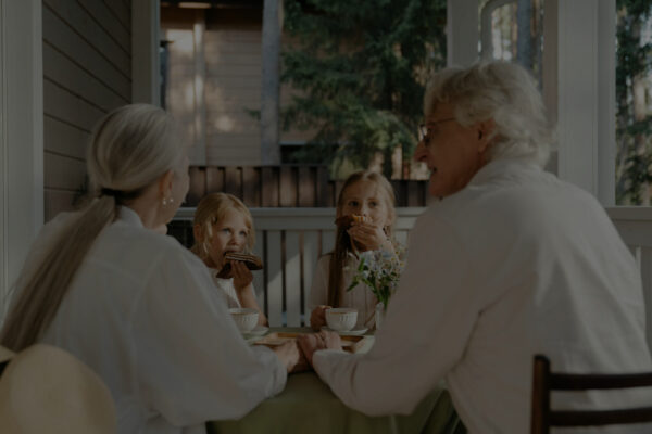 Gezin met volwassenen en kinderen die samen aan tafel zitten, als illustratie voor het belang van aanvullende vaccinaties voor alle leeftijden.