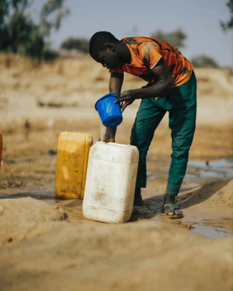 Persoon die water verzamelt in een gebied met beperkte toegang tot schoon drinkwater, als illustratie van het risico op cholera.