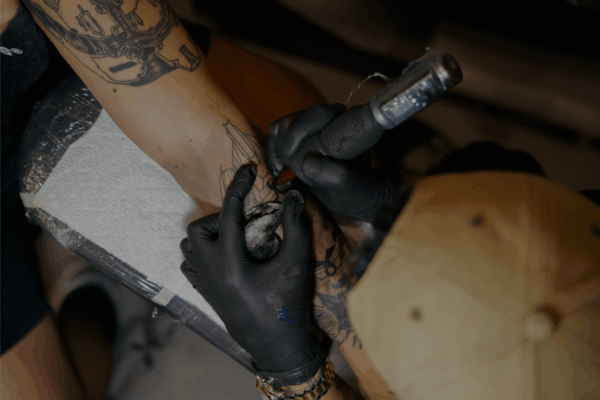 Close-up van een tatoeëerder die een tatoeage zet, als illustratie van het risico op hepatitis B door contact met bloed of niet-steriele instrumenten.