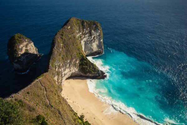 Luchtfoto van een kustlijn met helderblauw water en een verborgen strand op Nusa Penida in Indonesië.